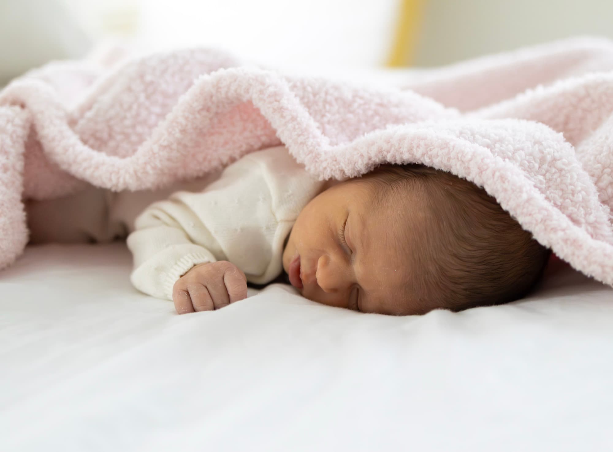 Newborn baby sleeping under pink blanket — peaceful newborn portrait