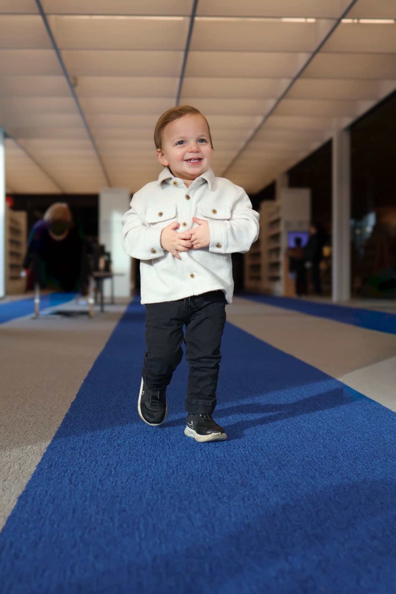 Toddler standing and smiling on blue carpet — child portrait