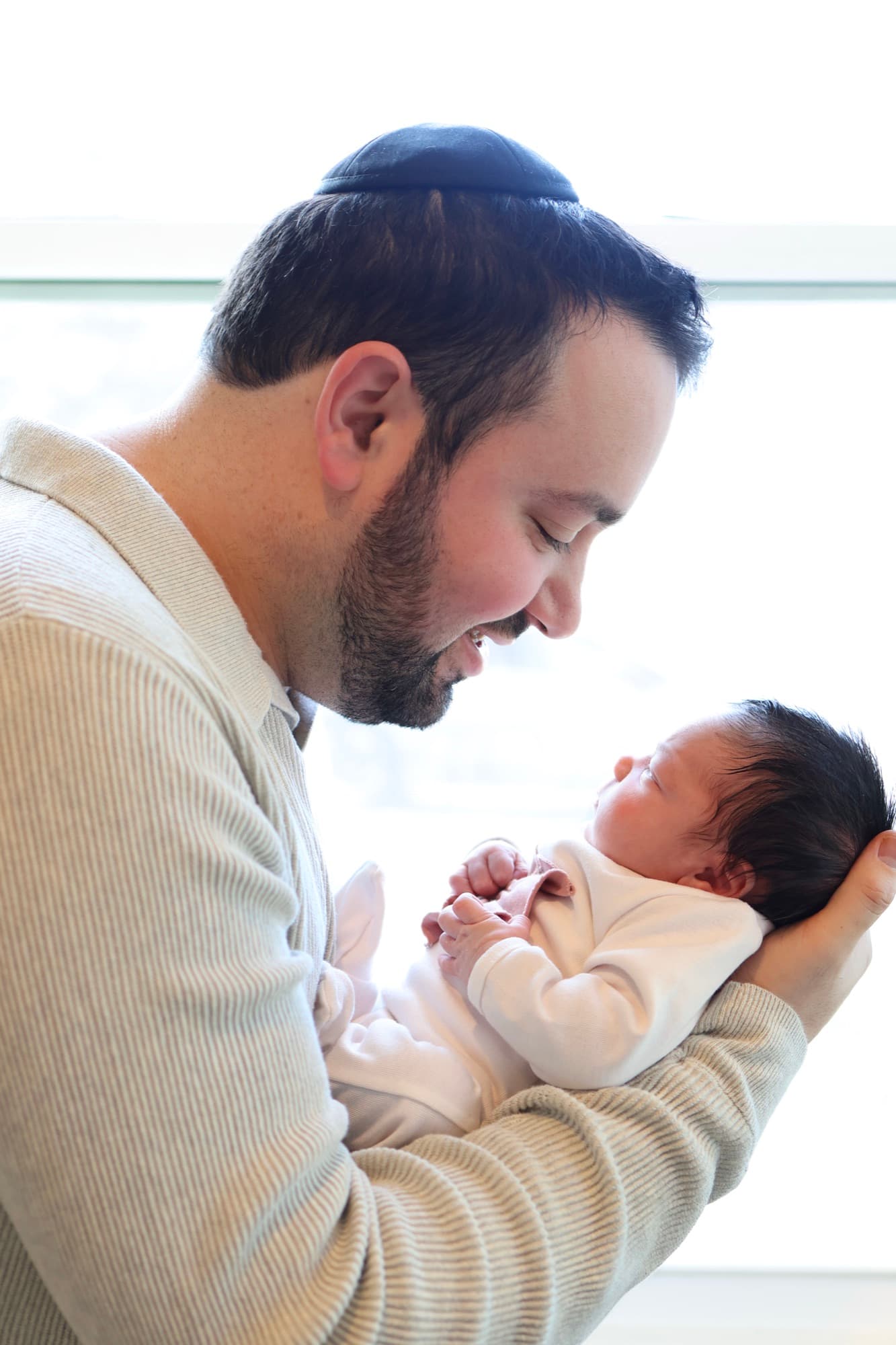 Father gazing at newborn by window — dad and baby portrait