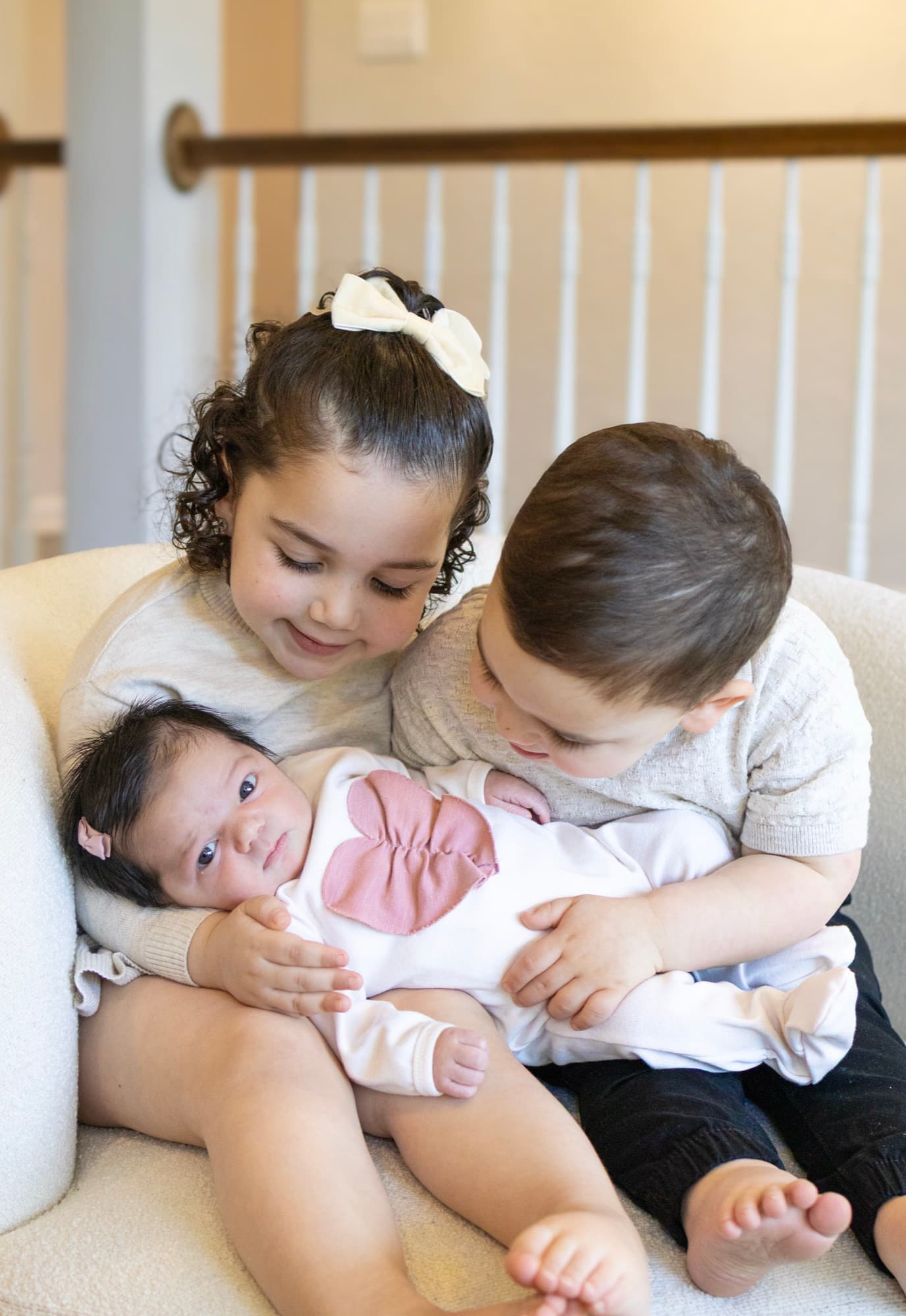 Siblings holding baby in chair — newborn family photography