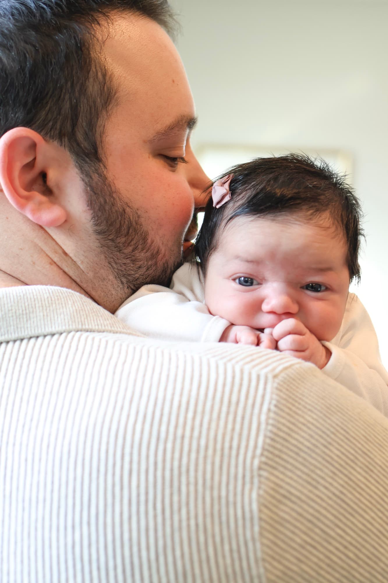 Father kissing newborn on head — dad and baby moment
