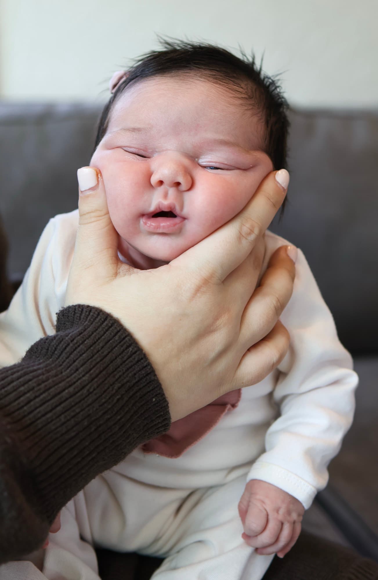 Father squishing newborn's cheeks — adorable baby moment