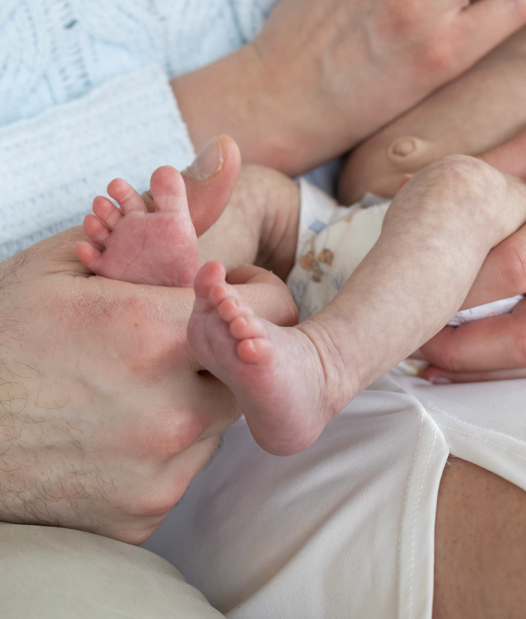 Tiny baby feet in father's hands — newborn detail photography