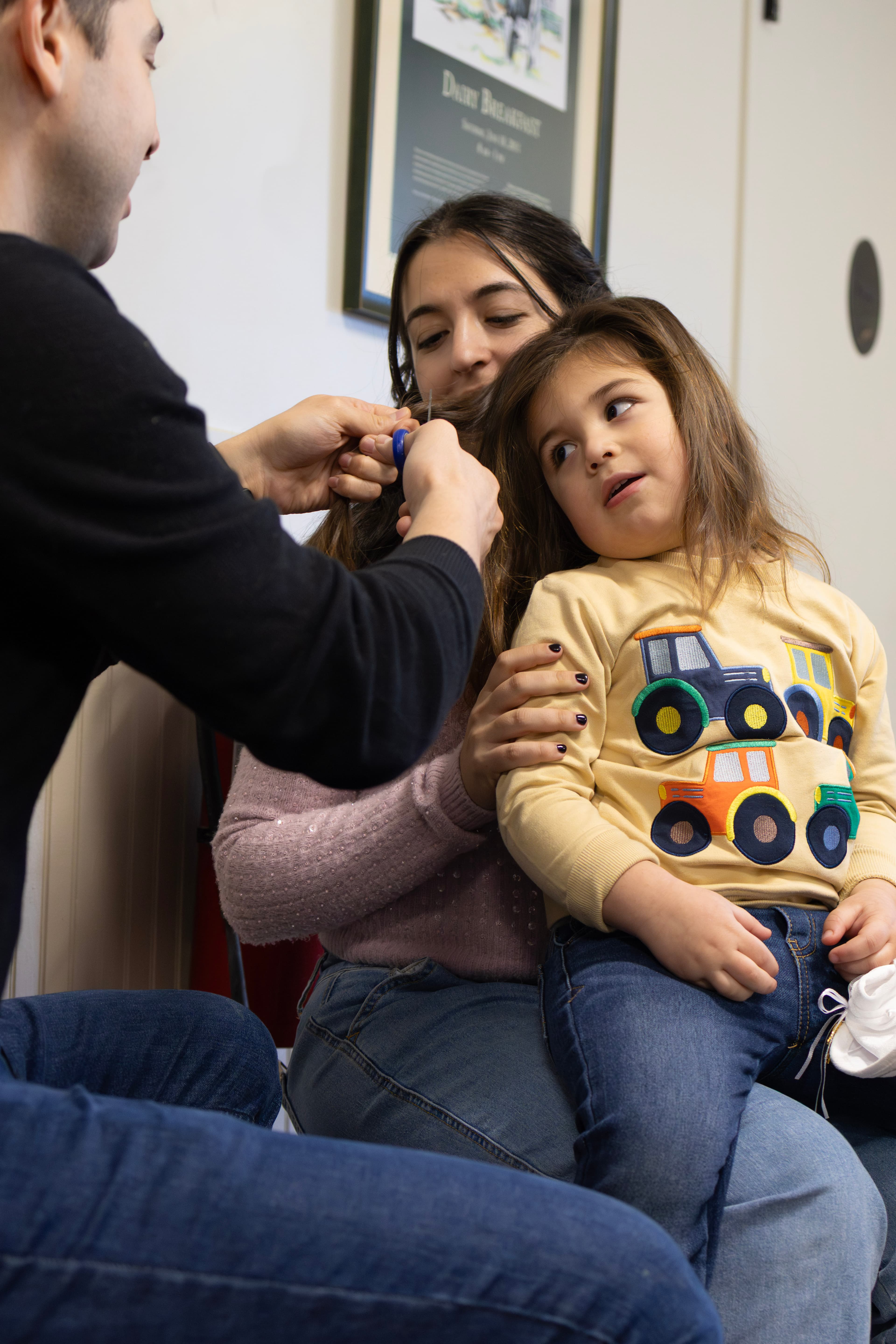 Father cutting daughter's hair at Upshirin while mother holds her — first haircut ceremony