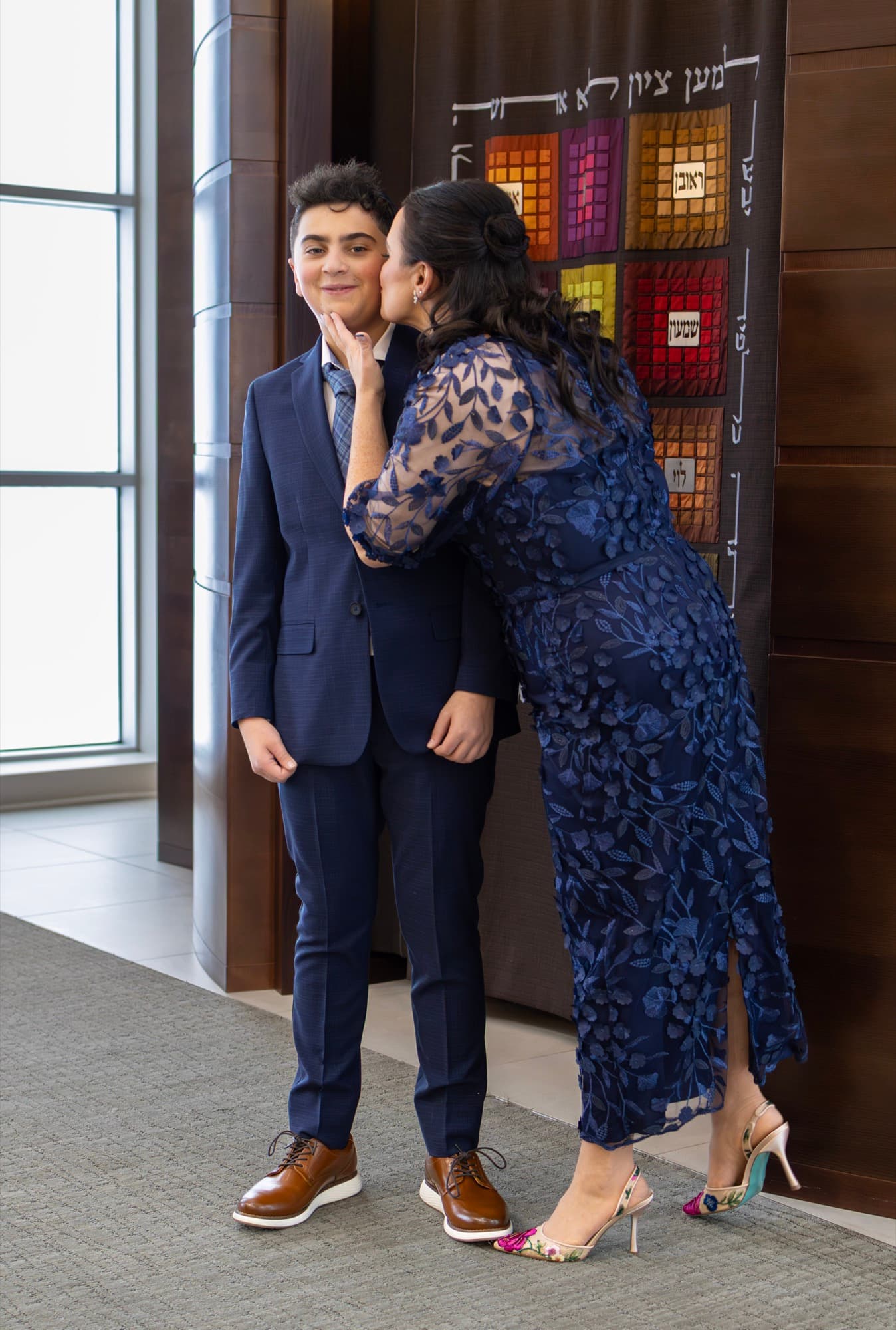 Mother kissing her son on his Bar Mitzvah day — tender family moment